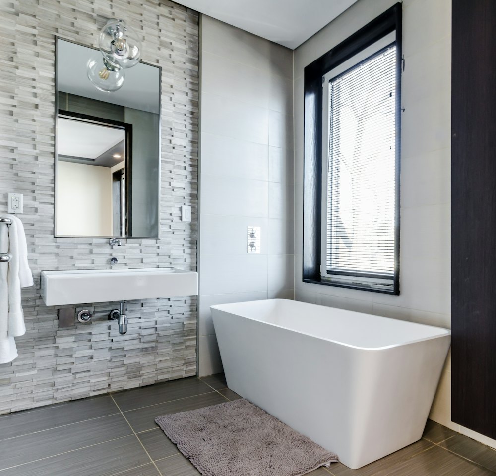 Baño reformado con bañera, lavabo y ventana
